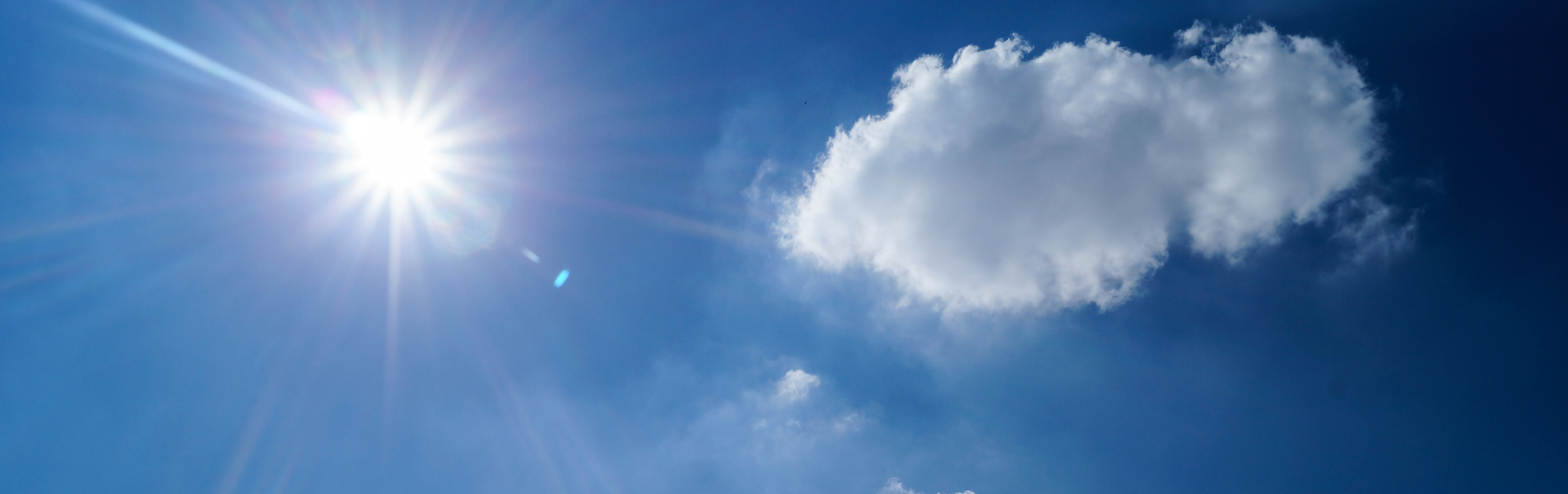 En blå himmel med en sol och ett moln.
