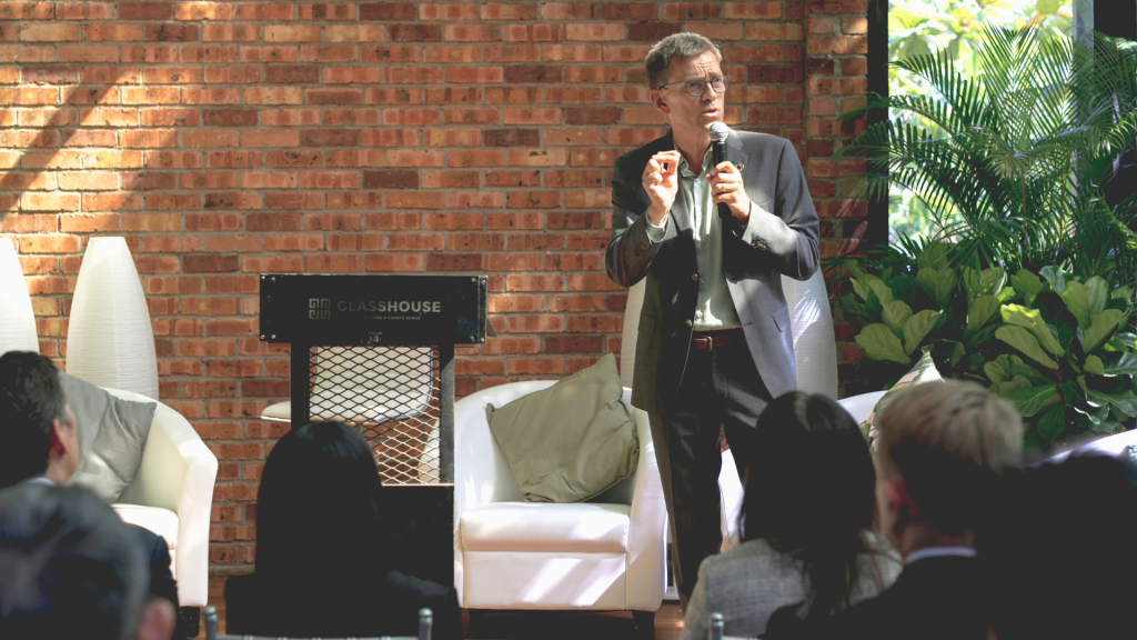 En man som håller i en mick och föreläser för personer.